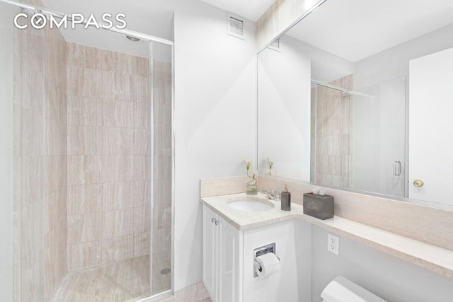 bathroom with visible vents, a shower stall, and vanity