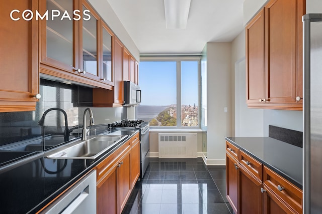 kitchen featuring dark tile patterned floors, dark countertops, appliances with stainless steel finishes, baseboards, and radiator