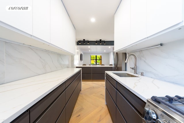 interior space with a sink, modern cabinets, light stone countertops, and white cabinetry