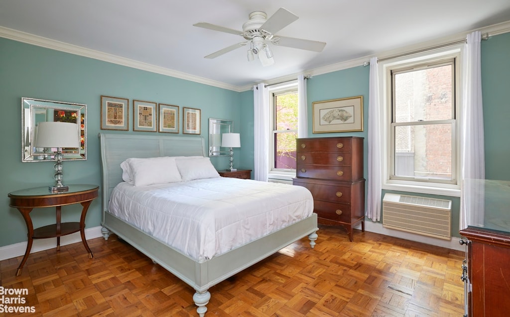 bedroom with crown molding, baseboards, ceiling fan, and a wall mounted AC