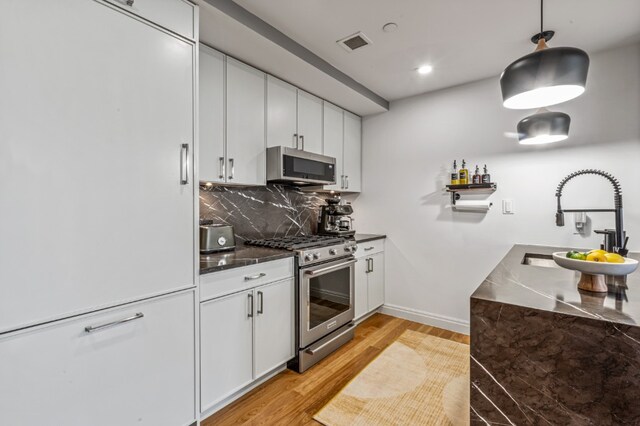 554 4th Ave Unit 3D, New York City, NY 11215 - kitchen featuring stainless steel appliances, light wood-style flooring, dark countertops, and tasteful backsplash