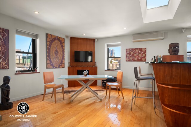 115 E 61st St Ph, Ph, New York City, NY 10065 - dining area featuring an AC wall unit, baseboards, light wood-style floors, recessed lighting, and a skylight