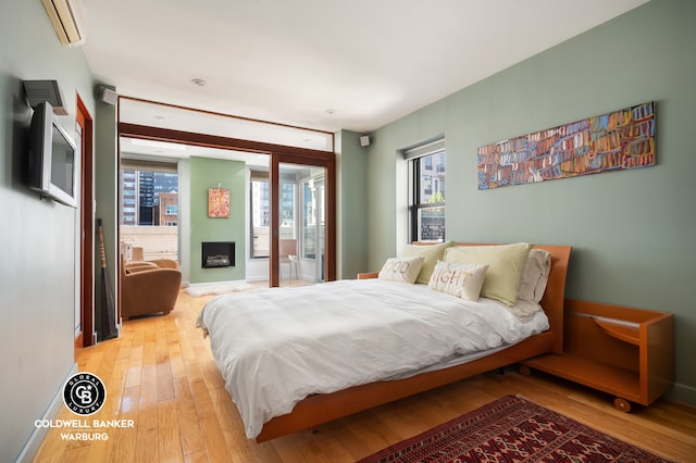 115 E 61st St Ph, Ph, New York City, NY 10065 - bedroom featuring light wood-style floors, baseboards, a wall mounted air conditioner, access to outside, and a fireplace