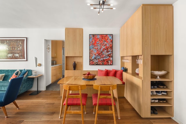 dining area featuring breakfast area, wood finished floors, and a notable chandelier