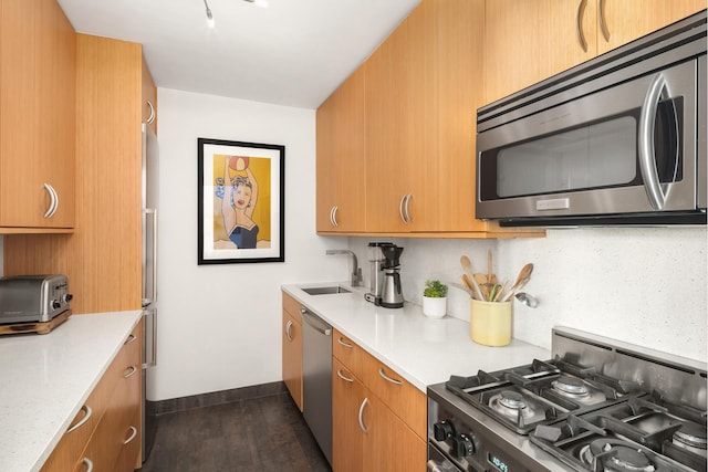 kitchen featuring a sink, dark wood finished floors, stainless steel appliances, baseboards, and tasteful backsplash