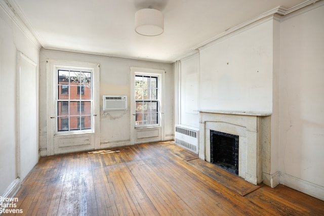 unfurnished living room with crown molding, radiator, hardwood / wood-style floors, and a fireplace with flush hearth