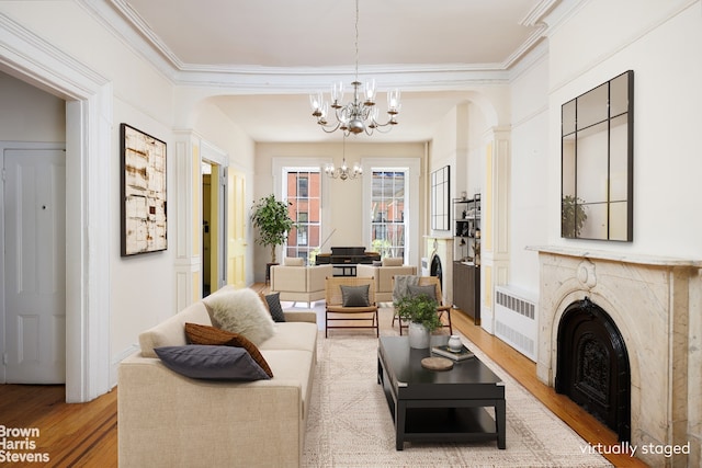 living room with a chandelier, ornamental molding, radiator heating unit, and wood finished floors