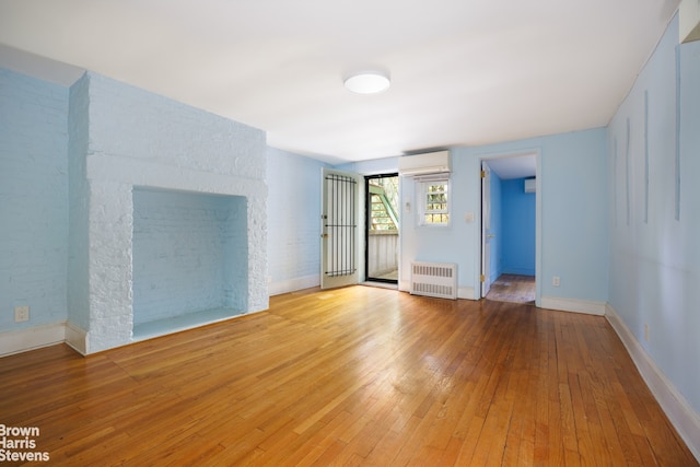 interior space with hardwood / wood-style flooring, a wall mounted AC, baseboards, and radiator