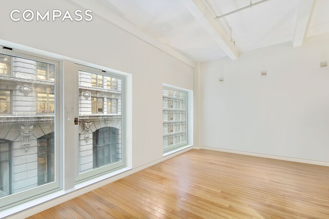 16 W 19th St Unit 3A, New York City, NY 10011 - unfurnished room with beamed ceiling, hardwood / wood-style floors, and baseboards