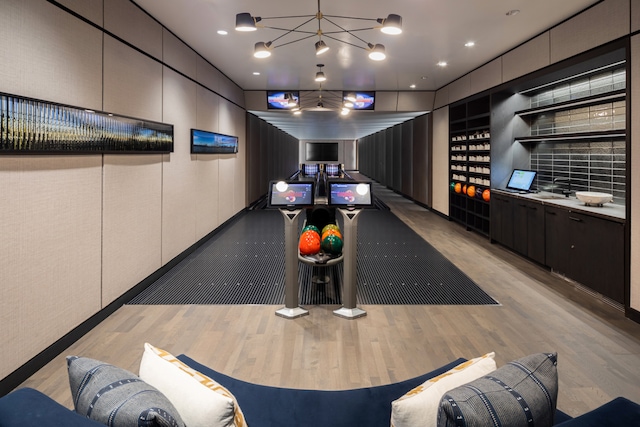 playroom with a sink, a bowling alley, a notable chandelier, and wood finished floors
