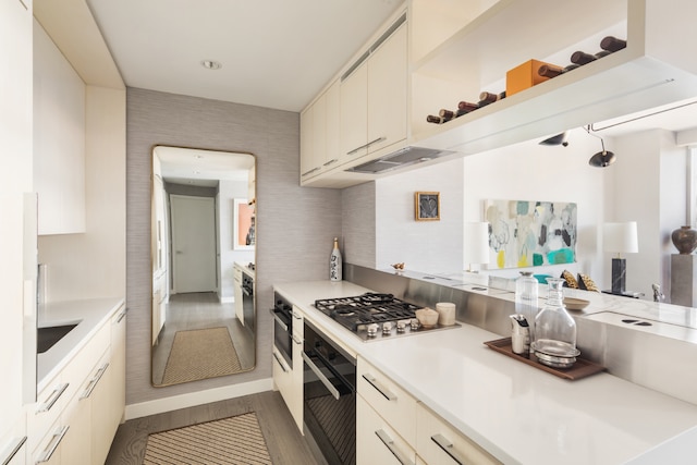 kitchen with stainless steel gas cooktop, oven, dark wood-style floors, light countertops, and under cabinet range hood