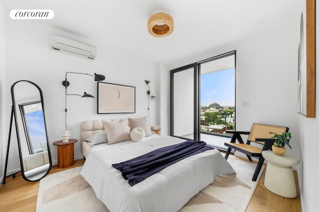 bedroom featuring access to outside, a wall mounted AC, visible vents, and light wood-style floors