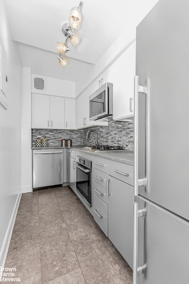 kitchen with visible vents, tasteful backsplash, light countertops, stainless steel appliances, and white cabinetry
