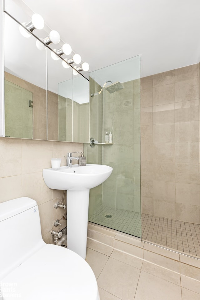 bathroom featuring tile patterned flooring, a tile shower, toilet, and tile walls