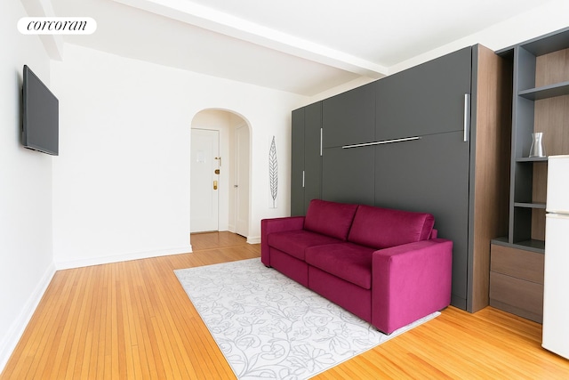 339 E 58th St Unit 2B, New York City, NY 10022 - living room featuring arched walkways, beamed ceiling, light wood-style floors, and baseboards