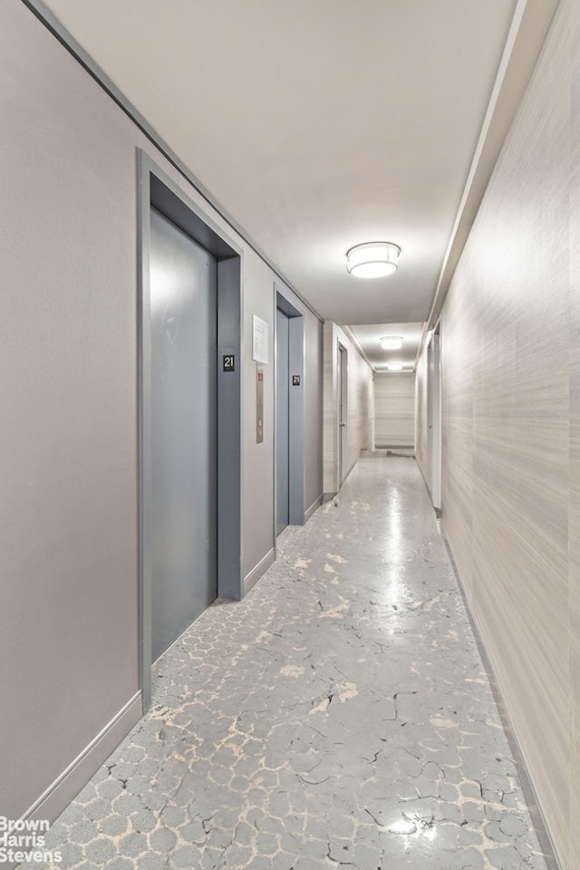 corridor with concrete flooring and elevator
