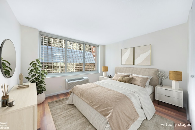 bedroom featuring baseboards, a wall unit AC, and wood finished floors