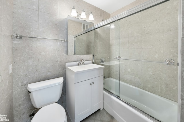 bathroom featuring vanity, toilet, tile walls, visible vents, and bath / shower combo with glass door
