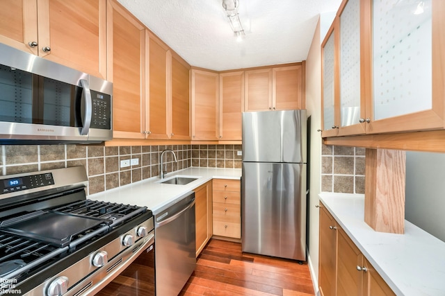 kitchen featuring light brown cabinetry, a sink, light wood finished floors, light countertops, and stainless steel appliances