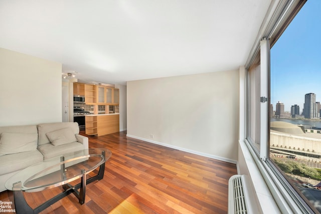 living area with baseboards, dark wood-style flooring, and a baseboard heating unit