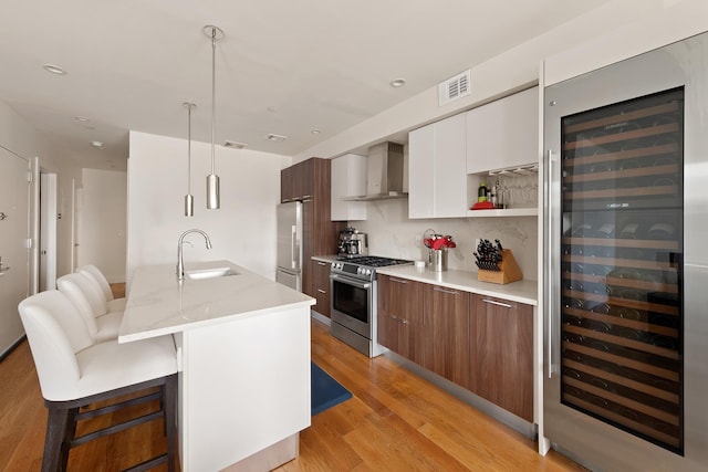 141 W 126th St Unit 4A, New York City, NY 10027 - kitchen with a sink, stainless steel appliances, wall chimney range hood, beverage cooler, and modern cabinets