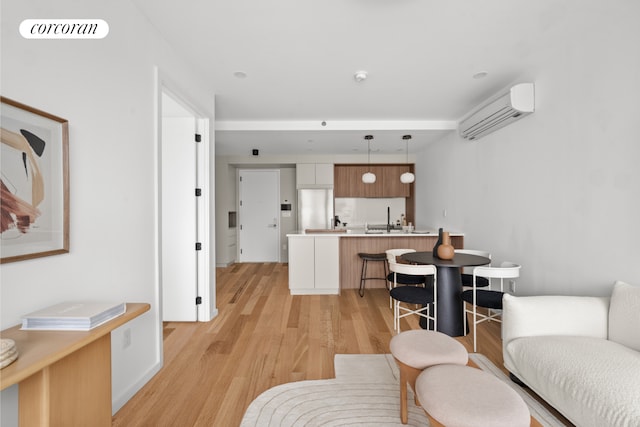 living room featuring an AC wall unit, light wood finished floors, and visible vents