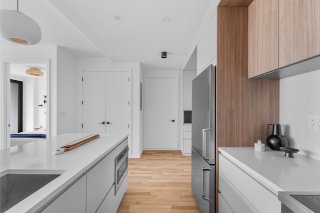 kitchen featuring high end fridge, light countertops, modern cabinets, and oven