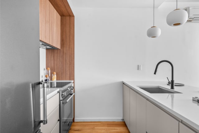 kitchen with a sink, light wood finished floors, light countertops, stainless steel appliances, and modern cabinets