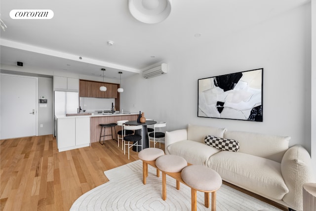 living area with visible vents, light wood finished floors, and a wall mounted air conditioner