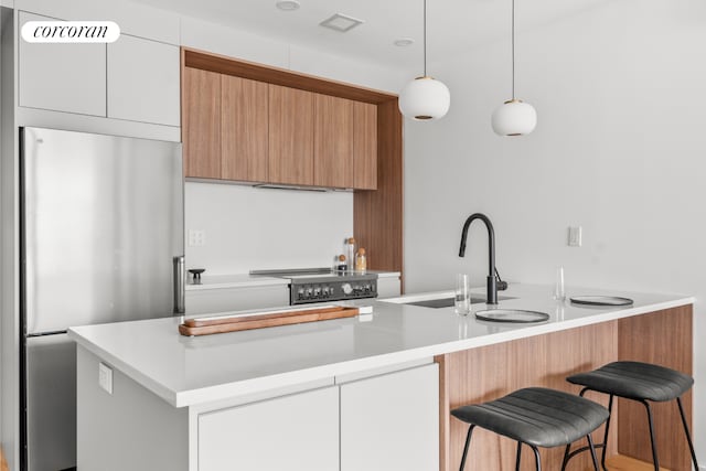 kitchen featuring visible vents, modern cabinets, a sink, freestanding refrigerator, and electric stove