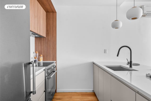 kitchen with a sink, light countertops, light wood-style flooring, stainless steel appliances, and modern cabinets
