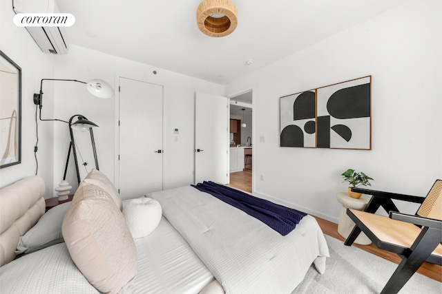 bedroom featuring a wall unit AC and wood finished floors