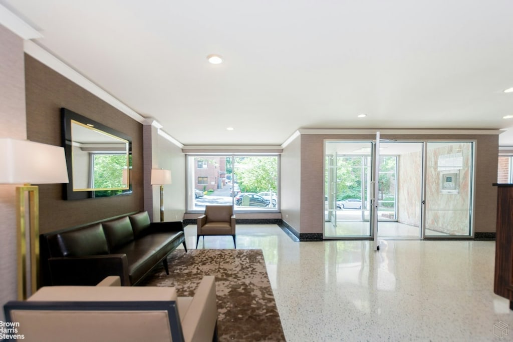 interior space with baseboards, ornamental molding, speckled floor, and a wealth of natural light