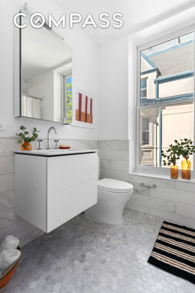 1370 Dean St Unit B, New York City, NY 11216 - full bath featuring plenty of natural light, tile walls, vanity, and wainscoting