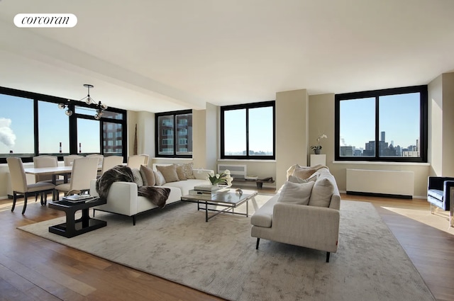 living room with radiator heating unit, a notable chandelier, wood finished floors, and visible vents