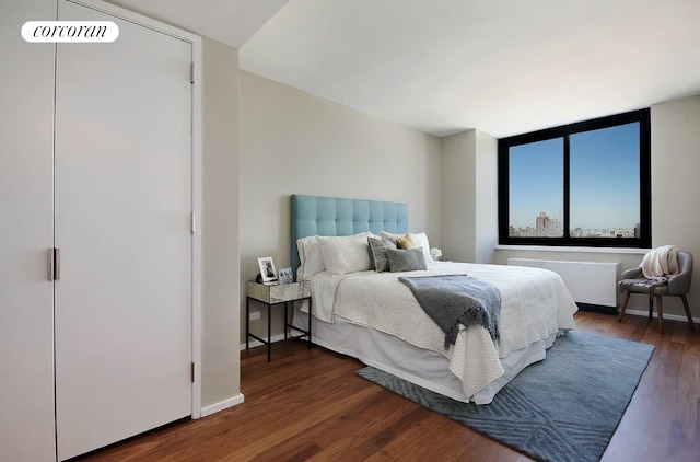 bedroom with radiator heating unit, baseboards, and dark wood finished floors