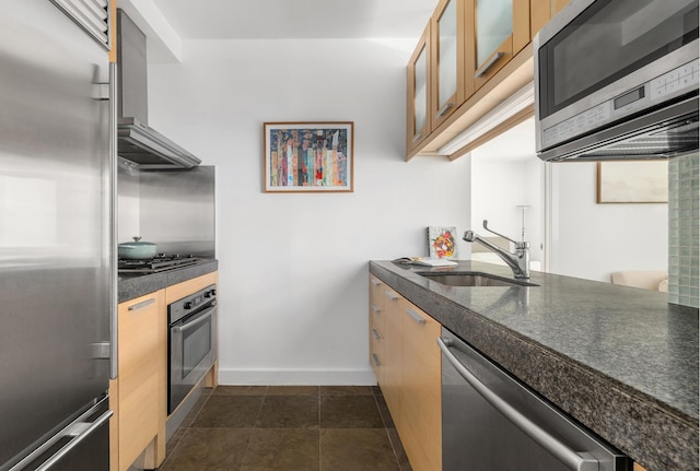 408 E 79th St Unit 3B, New York City, NY 10075 - kitchen featuring appliances with stainless steel finishes, wall chimney exhaust hood, a sink, baseboards, and glass insert cabinets