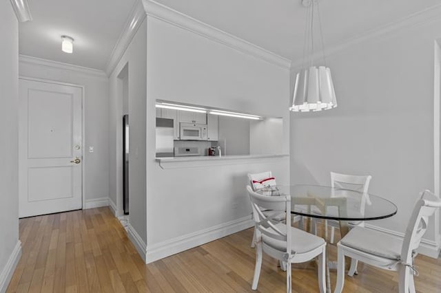 dining area featuring light wood-type flooring, ornamental molding, and baseboards