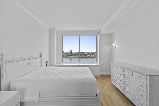 bedroom featuring ornamental molding, light wood-type flooring, and baseboards
