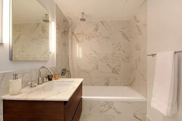 bathroom with tile walls, a combined bath / shower with rainfall shower, and vanity