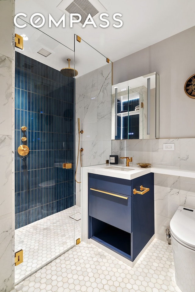bathroom with a tile shower, tile patterned flooring, vanity, toilet, and tile walls