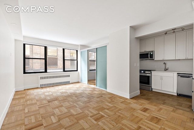 49 W 12th St Unit 1A, New York City, NY 10011 - kitchen with radiator heating unit, stainless steel appliances, baseboards, a sink, and light countertops