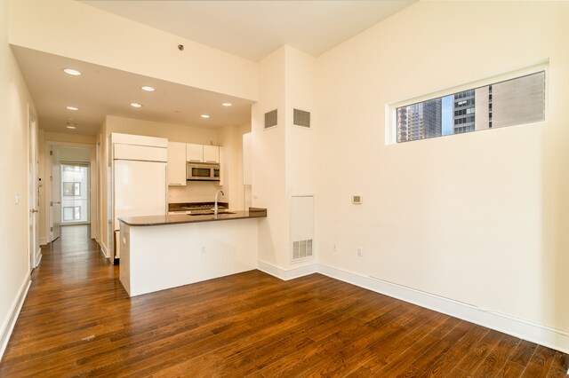 250 E 49th St Unit 10A, New York City, NY 10017 - kitchen featuring stainless steel microwave, dark countertops, dark wood-style floors, a sink, and recessed lighting