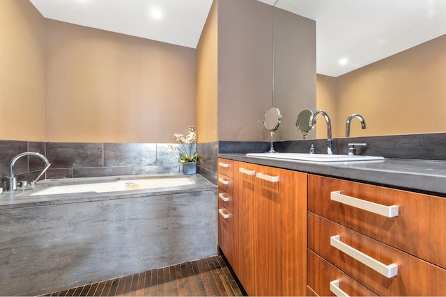 bathroom featuring a garden tub and vanity