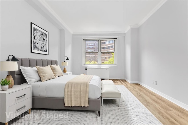 bedroom with baseboards, ornamental molding, radiator heating unit, and light wood-type flooring