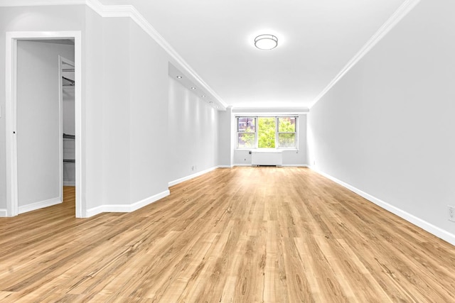 unfurnished living room featuring baseboards, ornamental molding, and light wood-type flooring