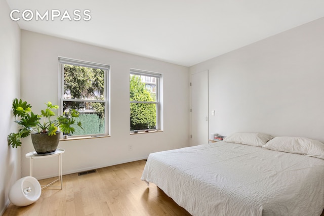 bedroom with baseboards, visible vents, and light wood-type flooring