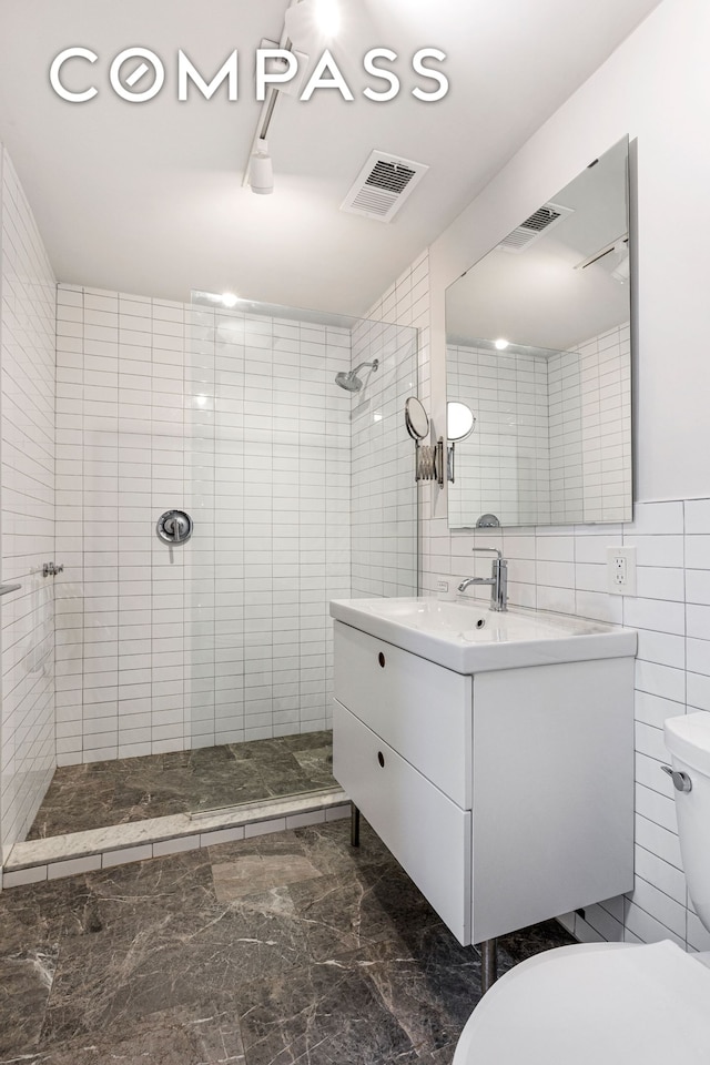 full bathroom featuring visible vents, vanity, toilet, tile walls, and tiled shower