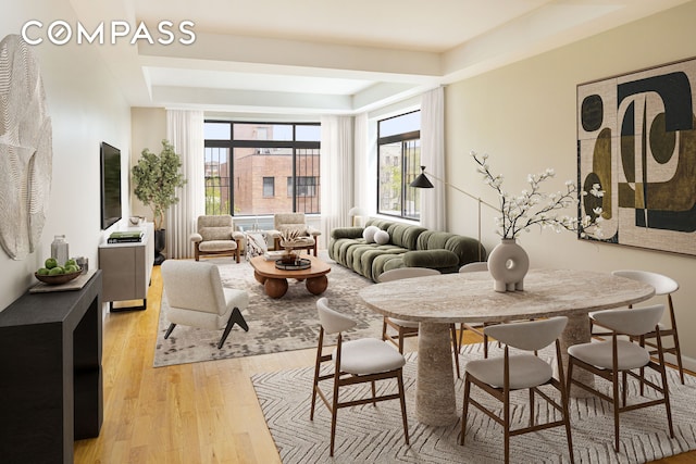 dining space featuring a tray ceiling and light wood-style floors