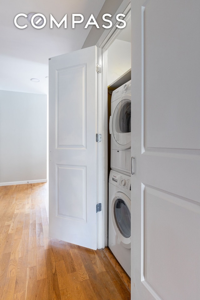 clothes washing area with estacked washer and dryer and light wood-style floors